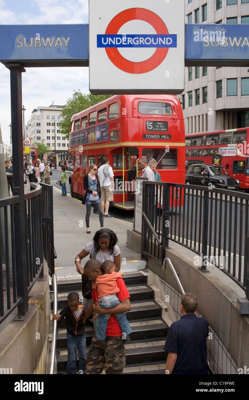 A red London route master bus on the Strand passes a London underground