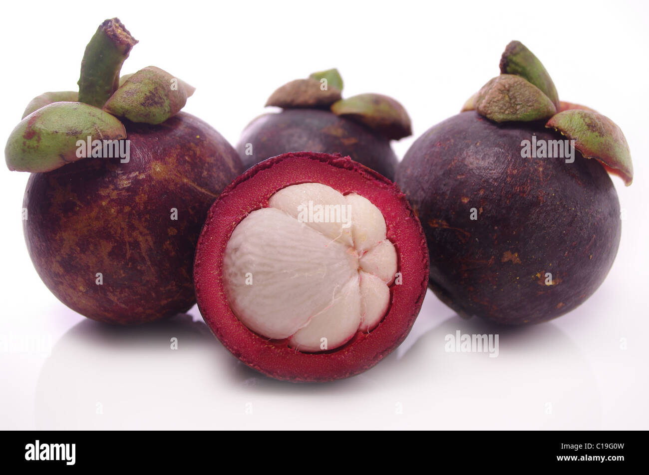 Mangosteen fruit and cross section showing the thick purple skin and white flesh of the queen of fruits. Stock Photo