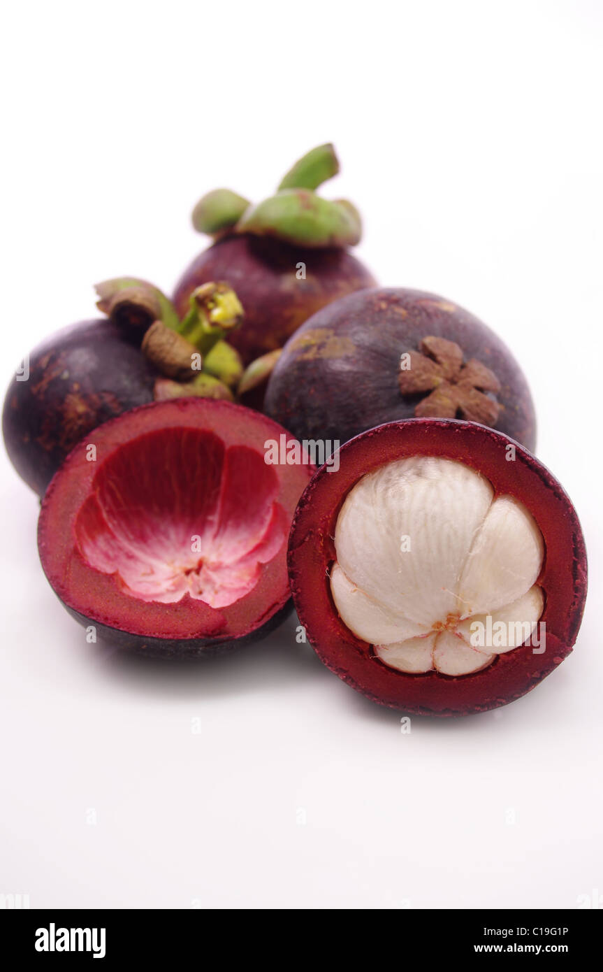 Mangosteen fruit and cross section showing the thick purple skin and white flesh of the queen of fruits. Stock Photo
