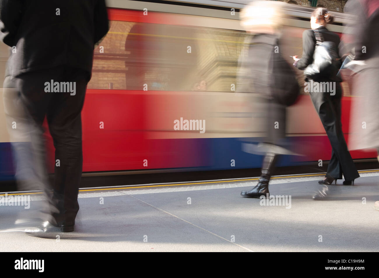 A London Underground train pulls in at a station as people rush to get ...