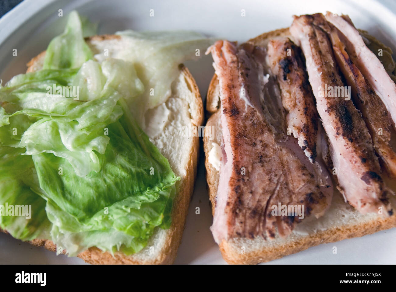 Grilled ham and lettuce on bread ready to be a sandwich at a picnic. Stock Photo
