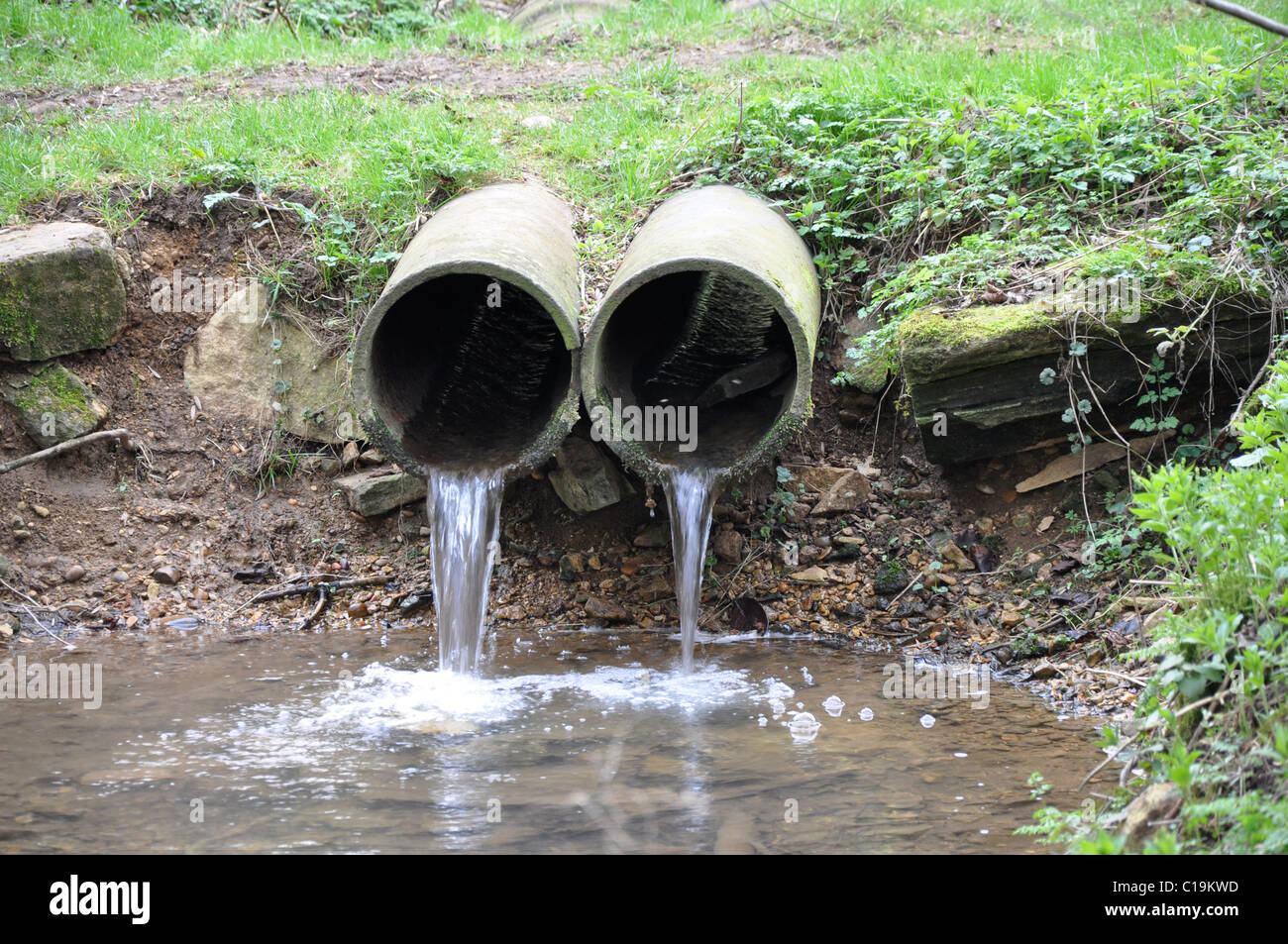 Pipes with water flowing into stream in english countryside Stock Photo ...
