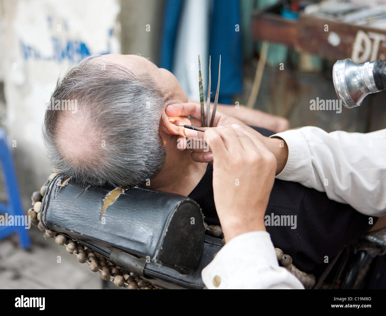 Ear cleaning by street barber on the streets of Hanoi, Vietnam Stock