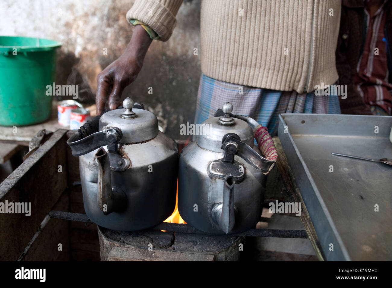 Two metal kettles of hot water at a roadside tea stand in Dhaka