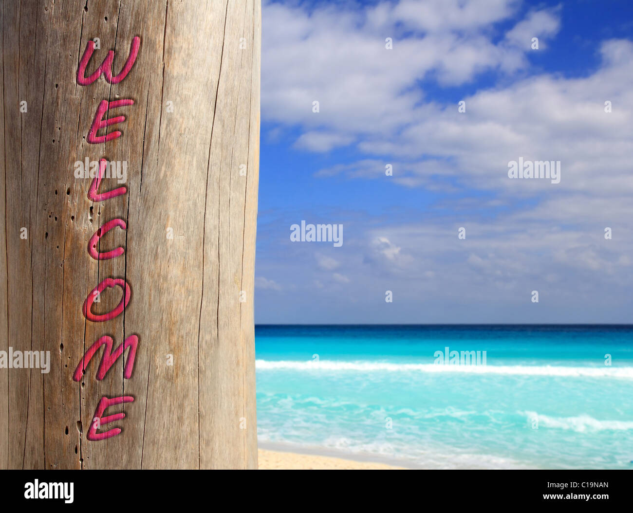 Caribbean tropical beach spell welcome written in wood trunk Stock Photo