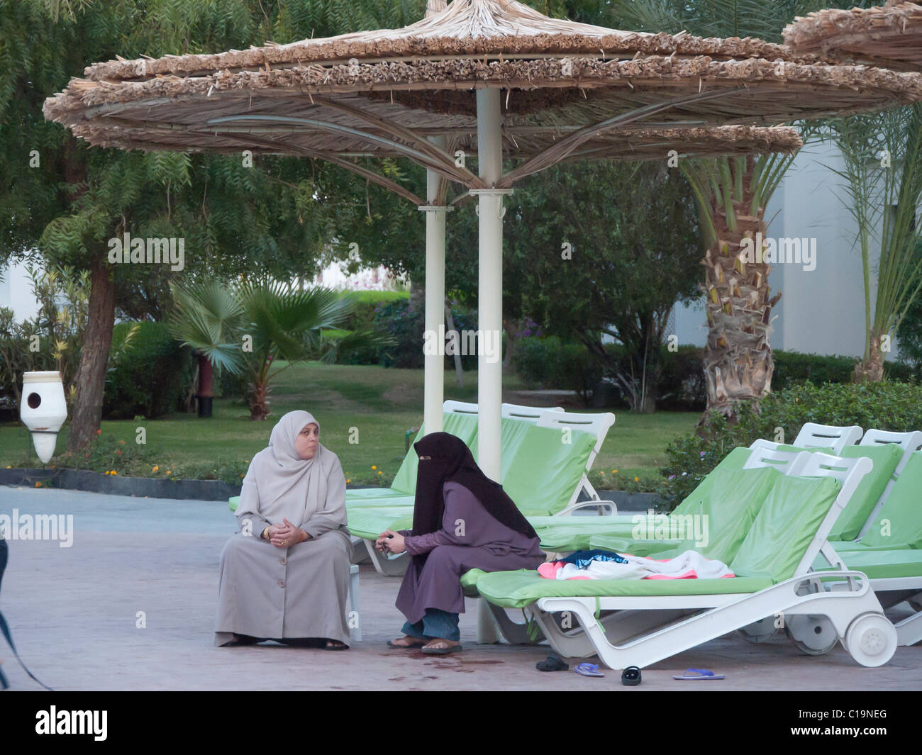 muslim women in burka and headscarfs chat beside swimming pool in Sharm el Sheikh, Egypt Stock Photo
