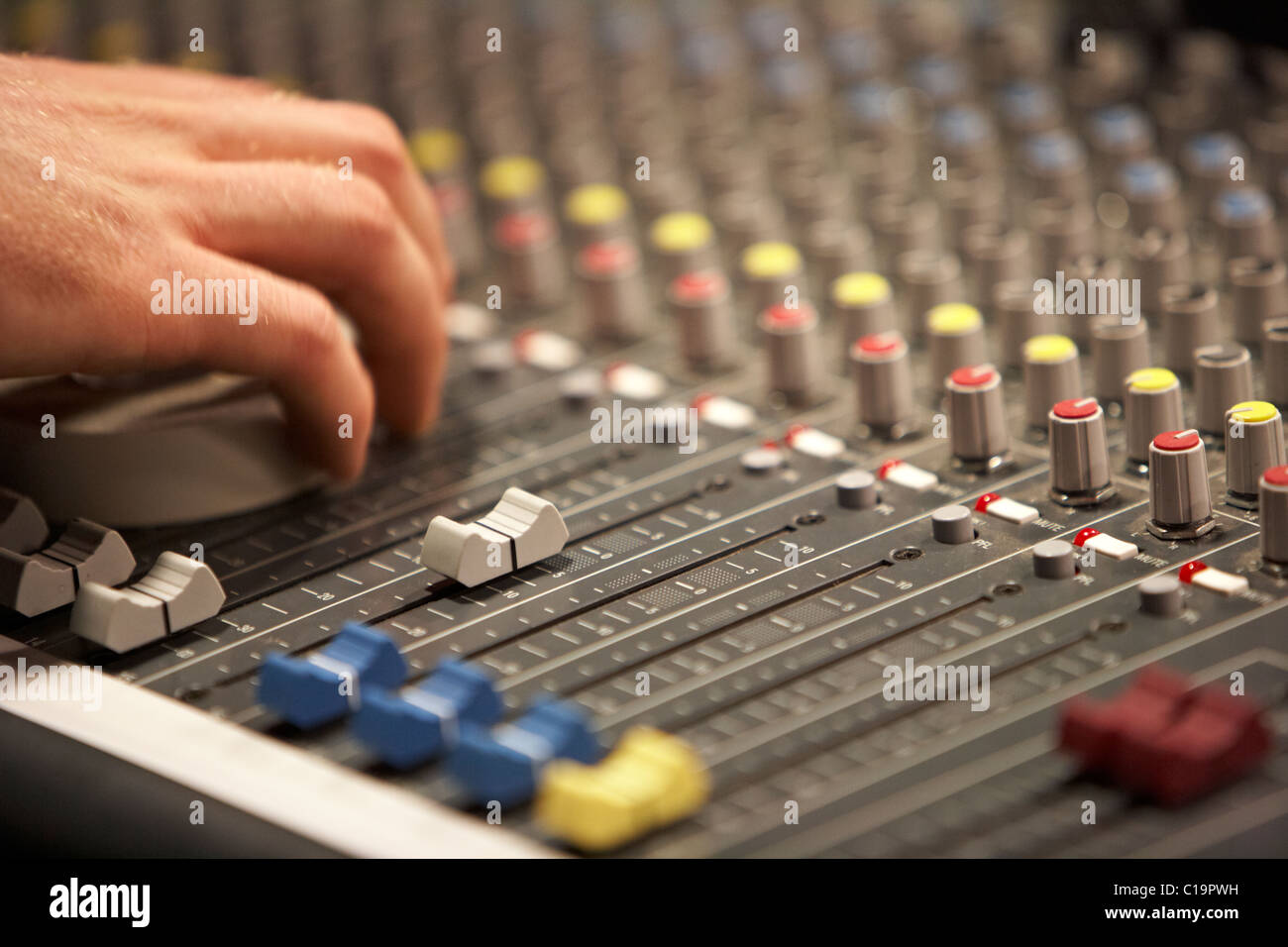 sliders and sound engineers hand on audio mixing desk in a theatre