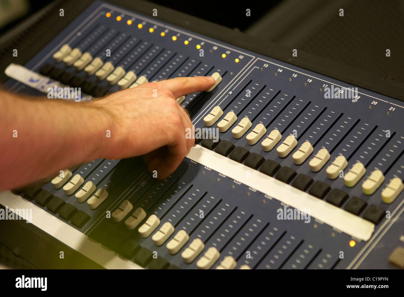lighting engineer adjusting sliders on a lighting mixing desk in a theatre concert hall Stock Photo