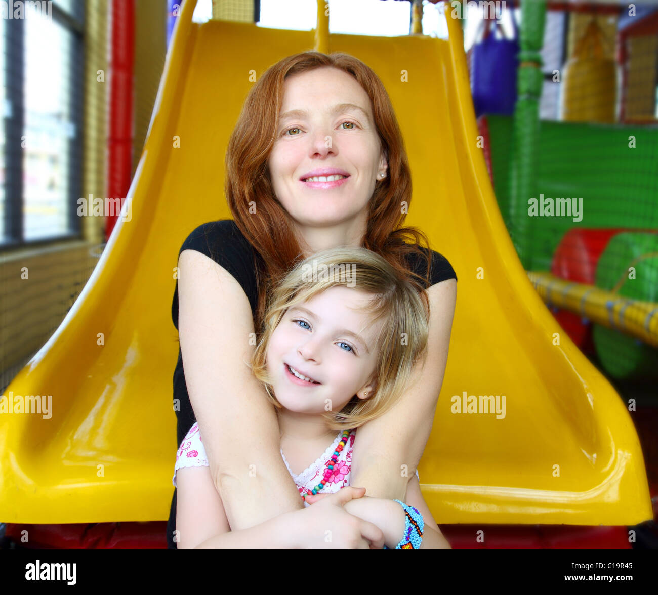 daughter and mother together in playground yellow slide Stock Photo - Alamy