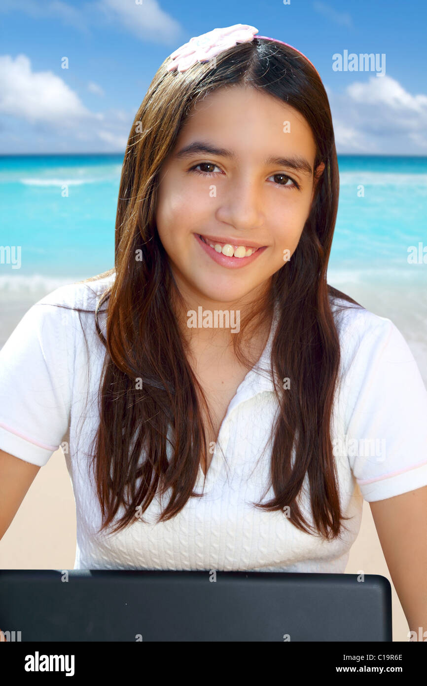 Latin teenager student smiling holding laptop in beach Stock Photo