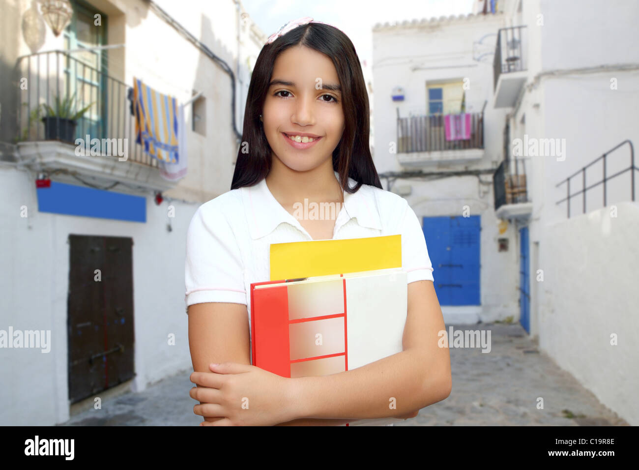 Brunette student young girl teen latin holding books white mediterranean village Stock Photo