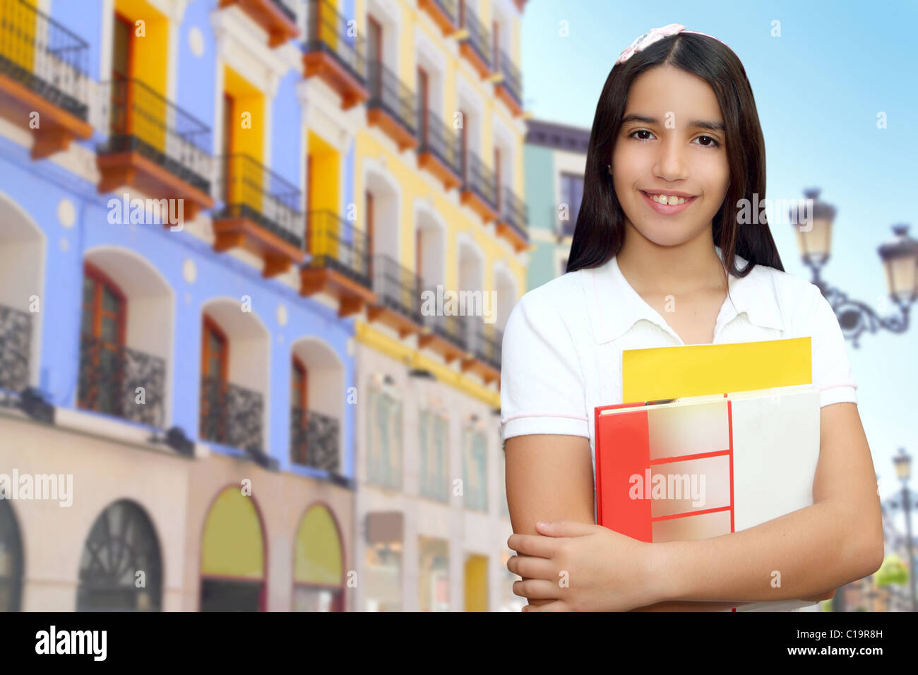 Brunette student young girl teen latin holding books colorful houses Stock Photo