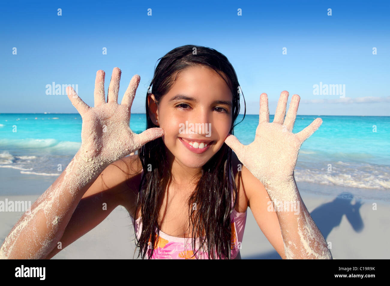 latin indian teen girl playing beach showing sandy hands in Caribbean tropical sea Stock Photo