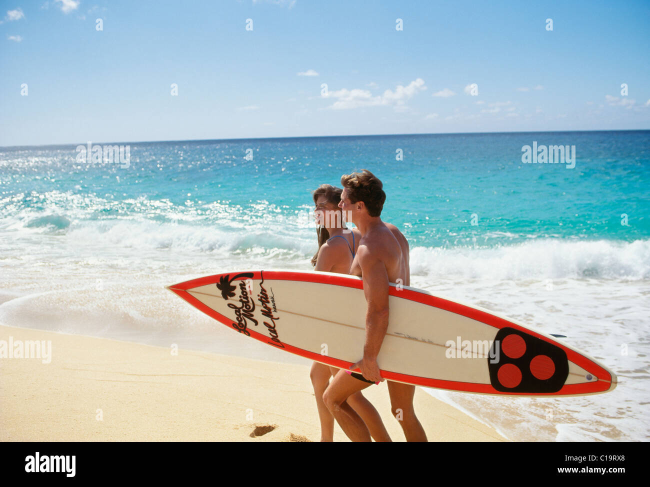 Couple walking on beach with surfboard, Hawaii Stock Photo