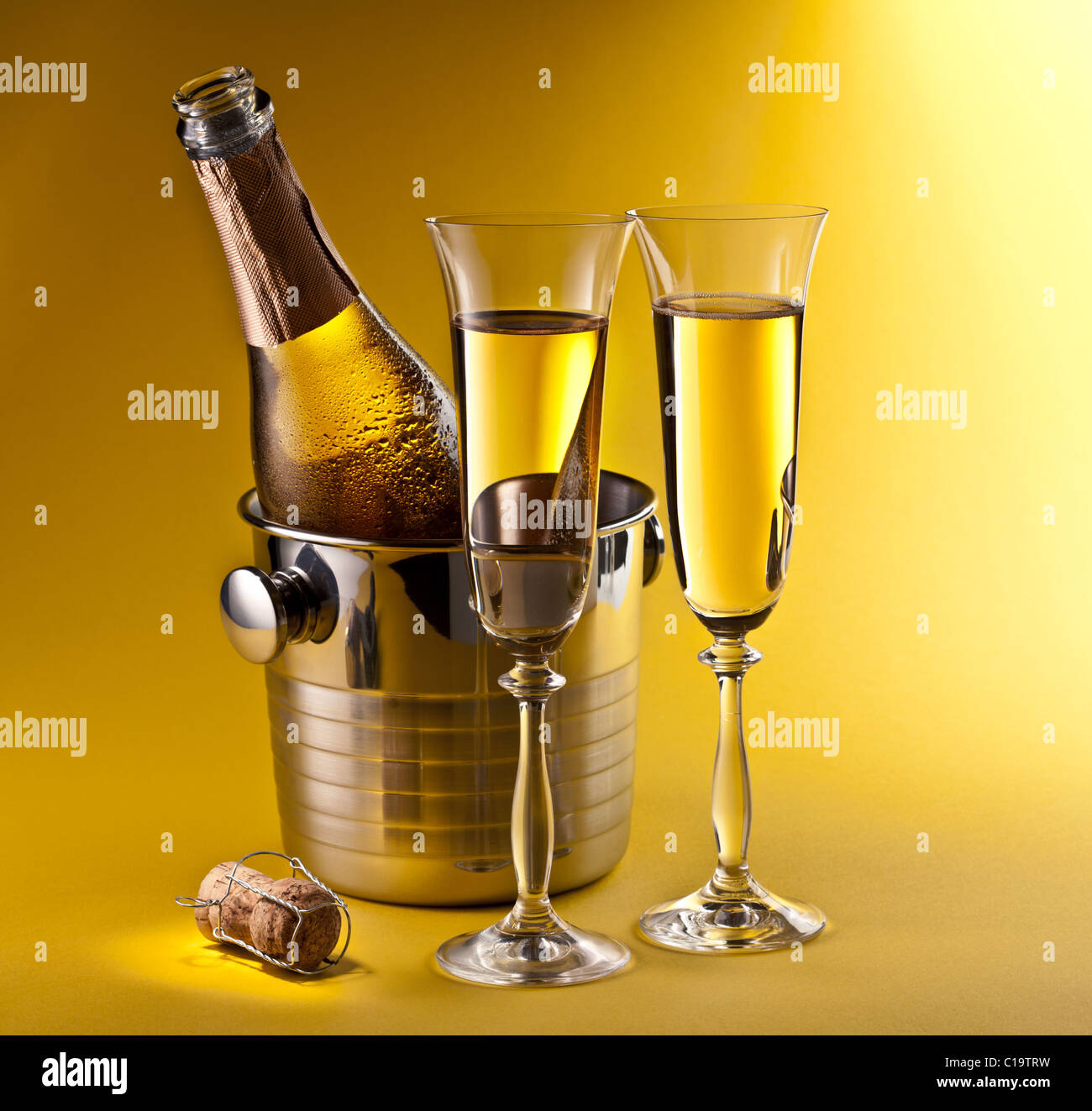 Champagne bottle in cooler and two champagne glasses. Isolated on a yellow. Stock Photo