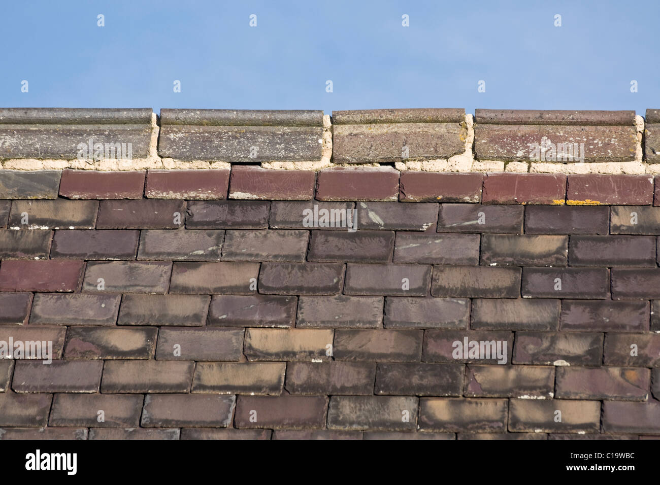 Ridge tiles on a church roof showing frost damage to the mortar. Stock Photo