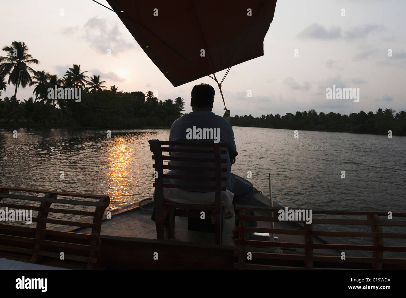 Man sitting on a chair on a boat, Kerala Backwaters, Alleppey, Alappuzha District, Kerala, India Stock Photo
