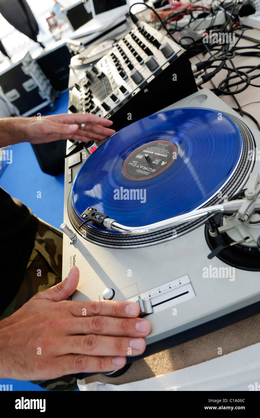 DJ performing live, mixing music using mixer and scratch vinyl record