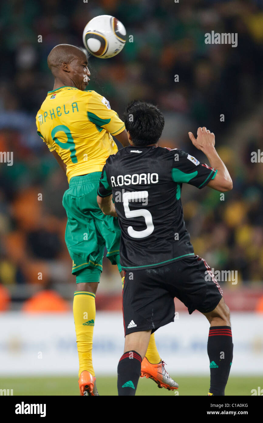 Katlego Mphela of South Africa (9) heads the ball over Ricardo Osorio of Mexico (5) during the 2010 World Cup opening match. Stock Photo