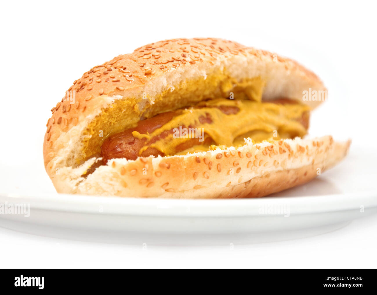 Oldfashioned hot dog with mustard, on a sesame seed bun. Shot on white