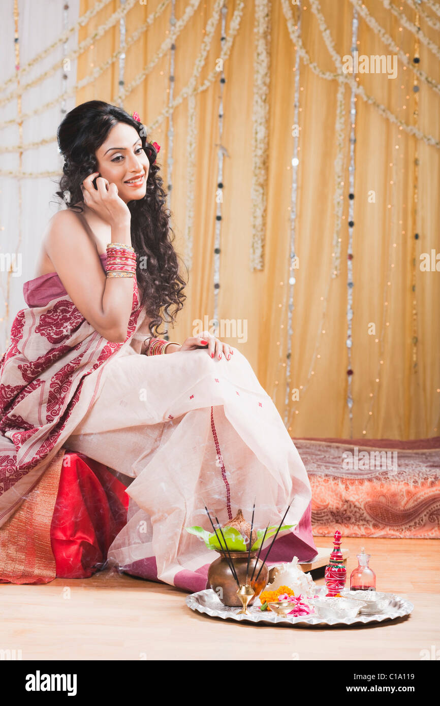 Bride in traditional Bengali dress talking on a mobile phone Stock Photo