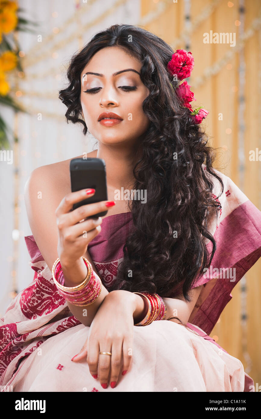 Bride in traditional Bengali dress text messaging on a mobile phone Stock Photo