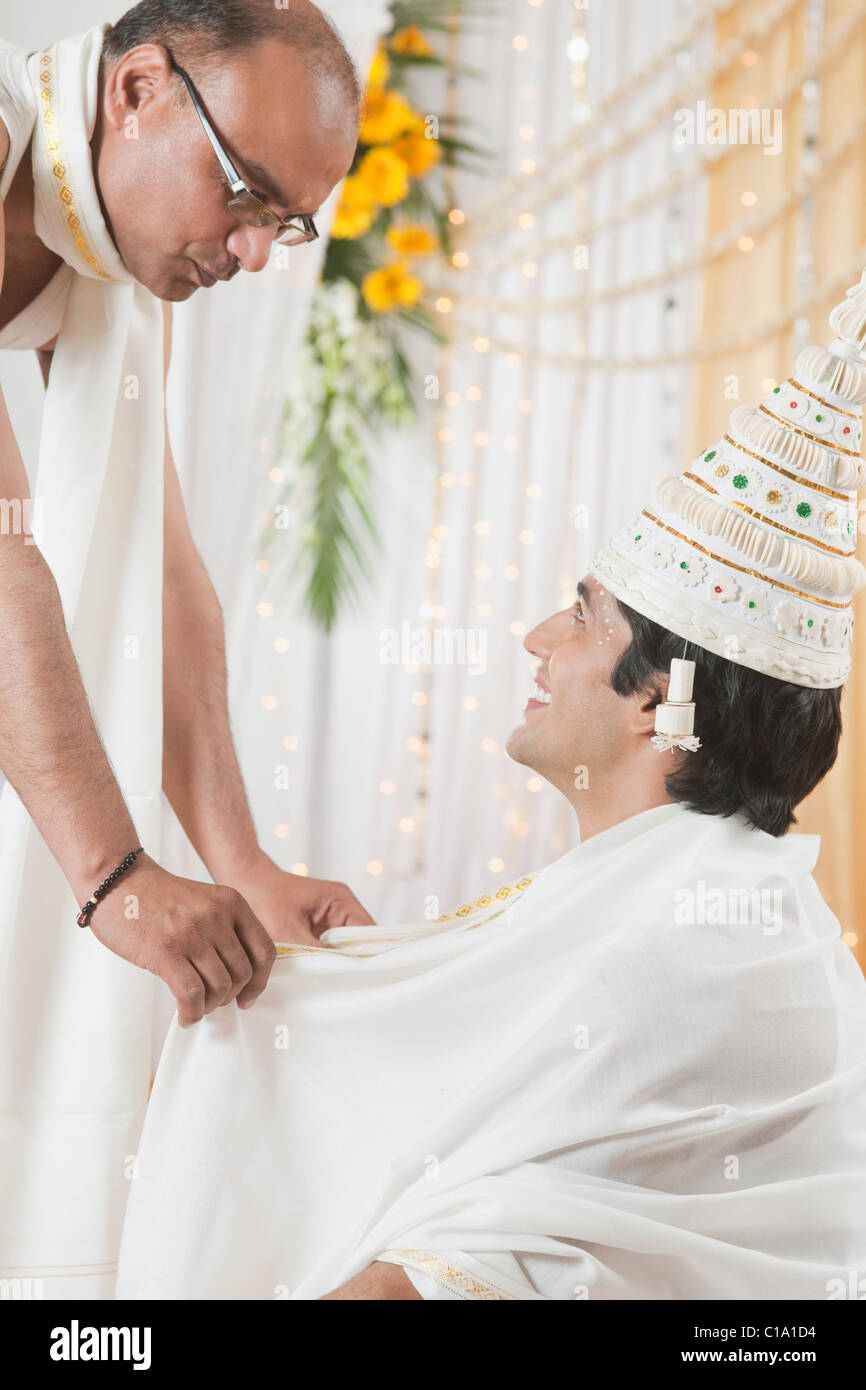 Bridegroom smiling with priest in wedding mandap during Bengali wedding Stock Photo
