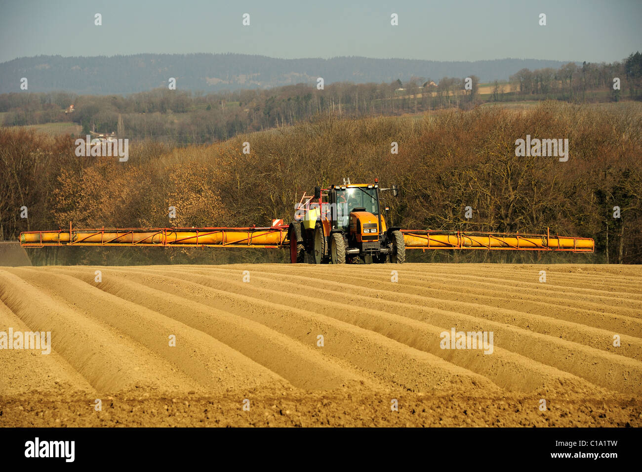 Spraying herbicide on a newly-planted potato field, prior to covering with fleece to protect against late frosts Stock Photo