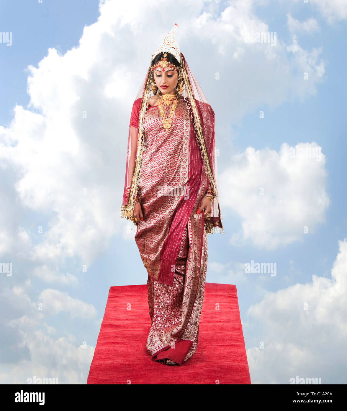 Bride in Bengali dress standing on a carpet in clouds Stock Photo