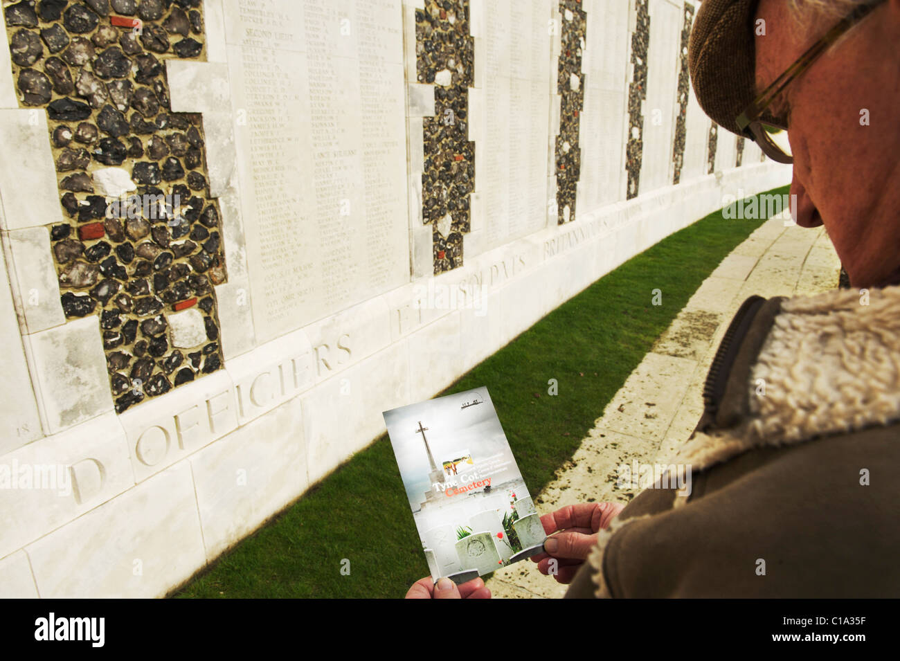 Elderly male reading tyne cot cemetery leaflet while standing in front names of the dead at the cemetery Stock Photo