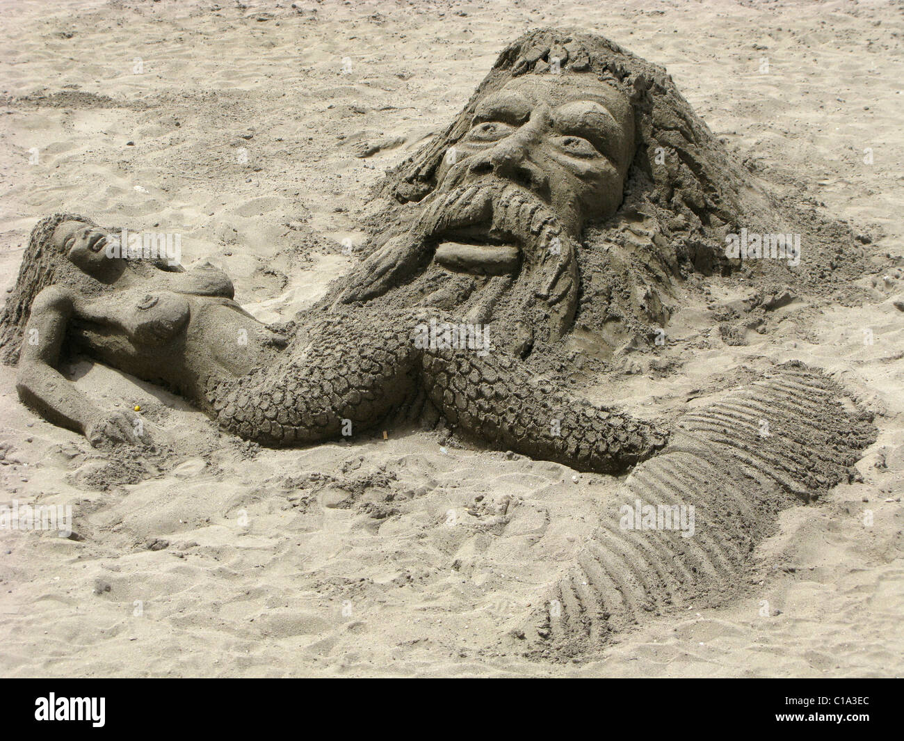 Neptune and mermaid in sand Stock Photo