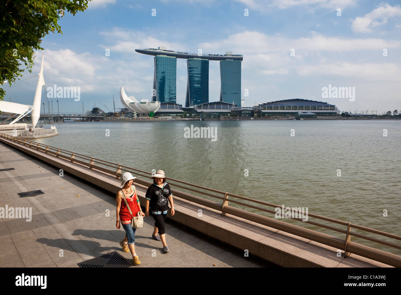 Women walking along the Marina Promenade with the Marina Bay Sands Singapore in the background.  Marina Bay, Singapore Stock Photo