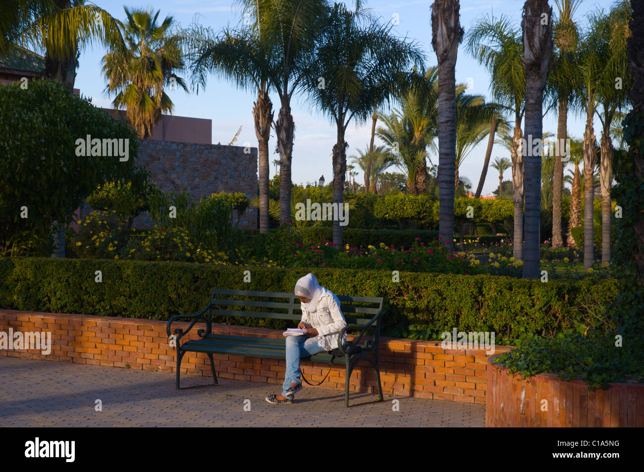 Local Arab women reading and writing Jardin de la Koutoubia park Marrakesh central Morocco Africa Stock Photo