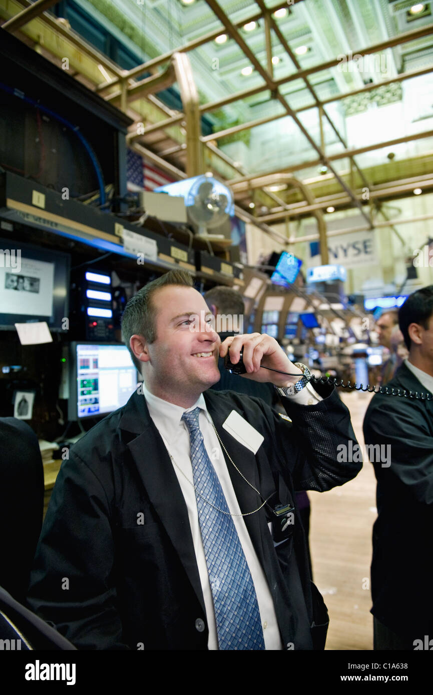 A Securities Trader consults the market-data screens around him while calling in a order. Stock Photo
