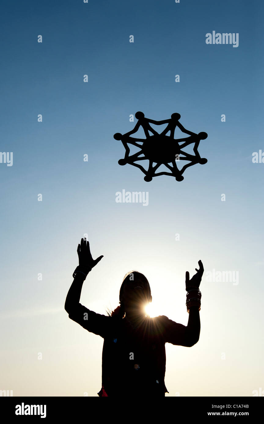 Silhouette indian girl throwing a symbol of one world, unity and humanity into the air. India Stock Photo