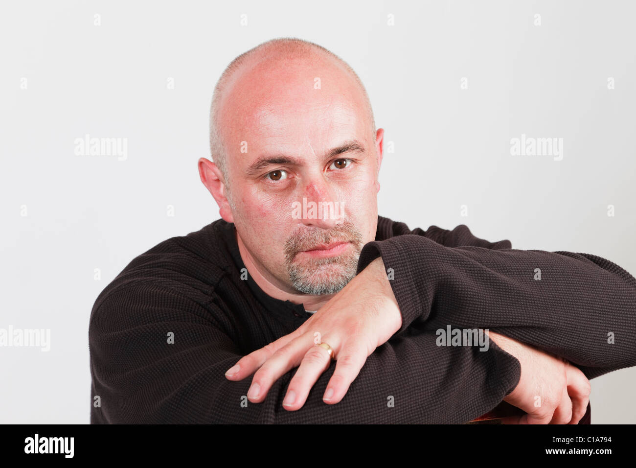 UK, Britain. Bald headed mature man with arms folded and a bored facial expression Stock Photo