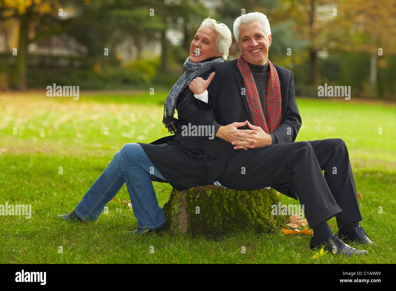 Couple sitting on tree trunk Stock Photo