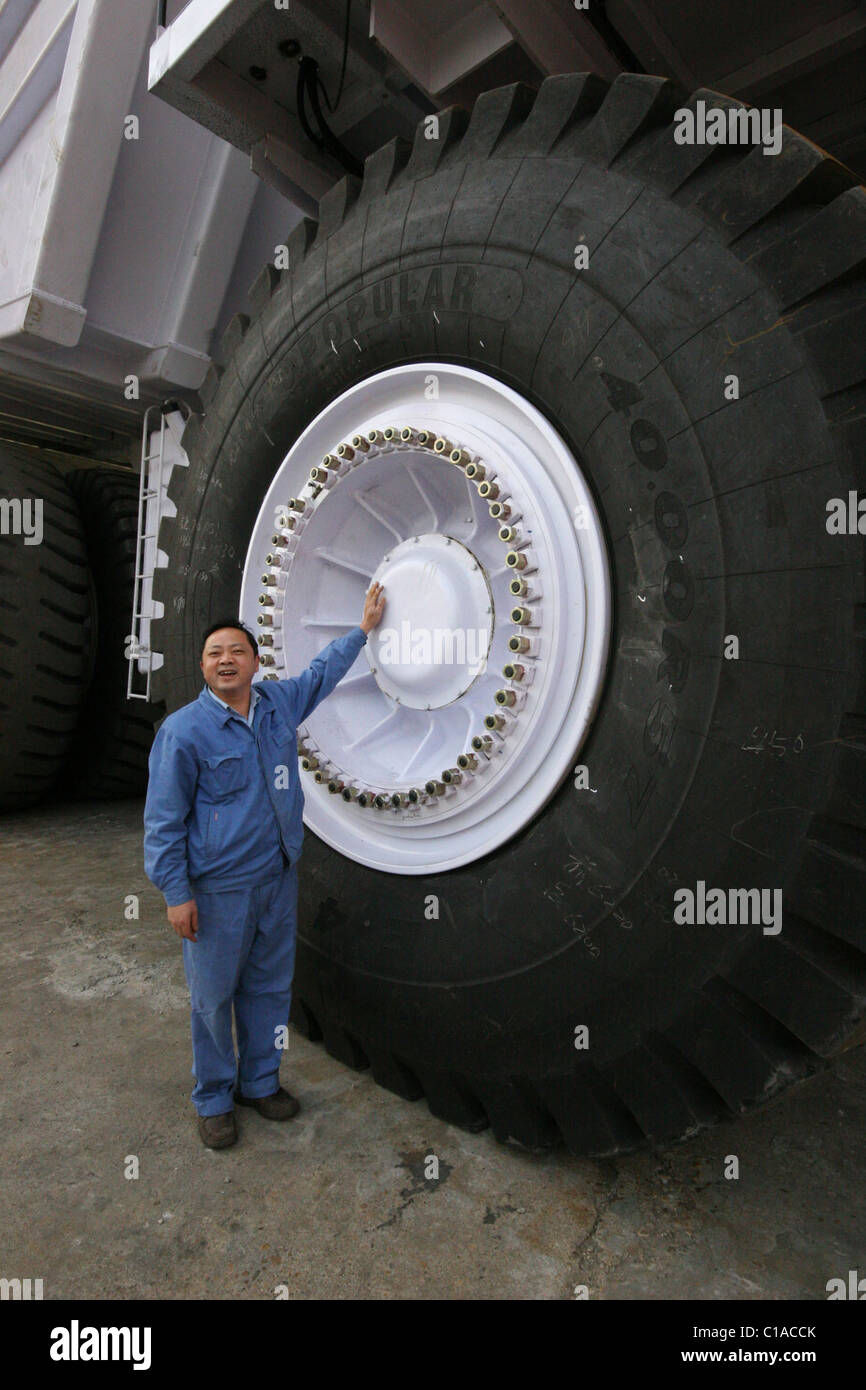 A worker stands beside the wheel of an AC drive electric dump car of 220 tonnage in Xiangtan  Hunan, China - 29.10.08 Stock Photo
