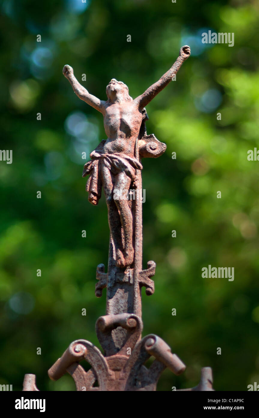 Rusty old Jesus statue without cross. Green forest in the background. Stock Photo