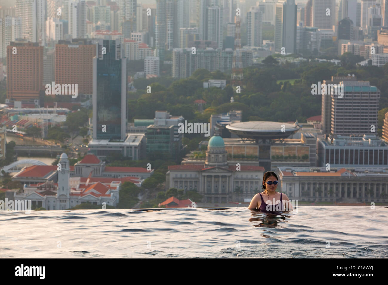 Woman swimming in pool at Marina Bay Sands SkyPark with city skyline in background.  Marina Bay, Singapore Stock Photo