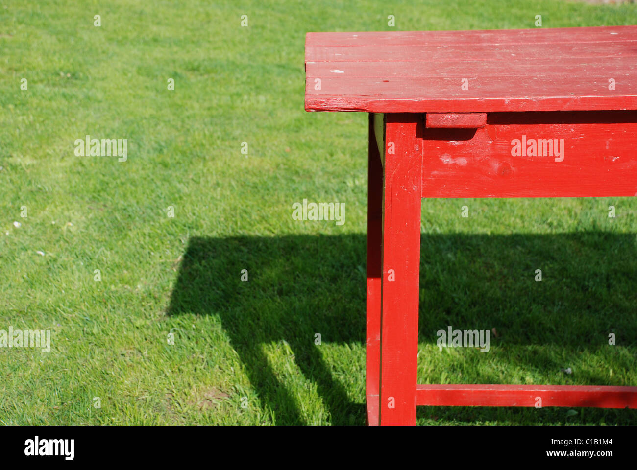 self made table of planks coloured red standing on the green grass Stock Photo