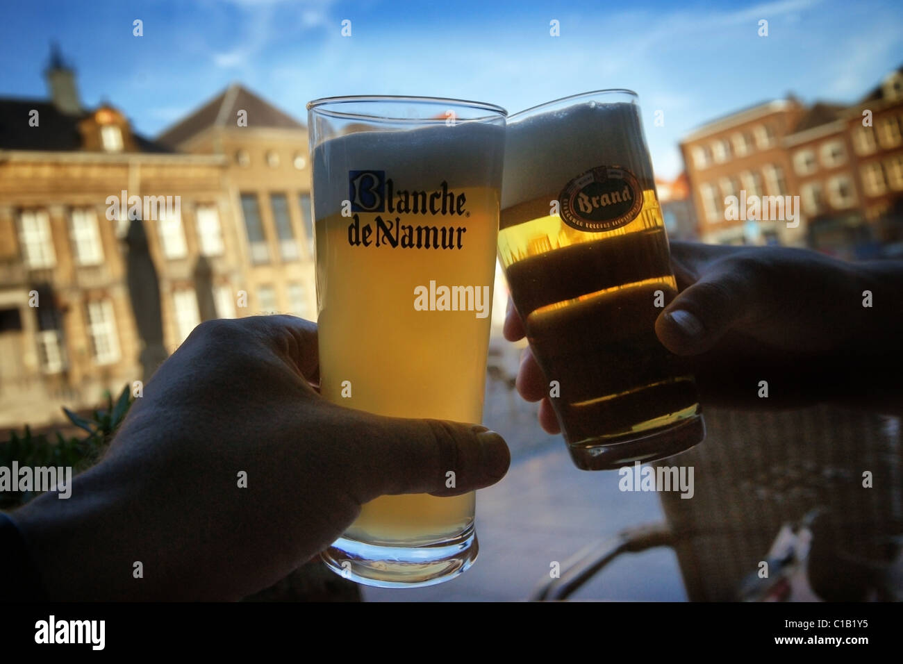 two toasting beer glasses in front of cityhall in Roermond Stock Photo