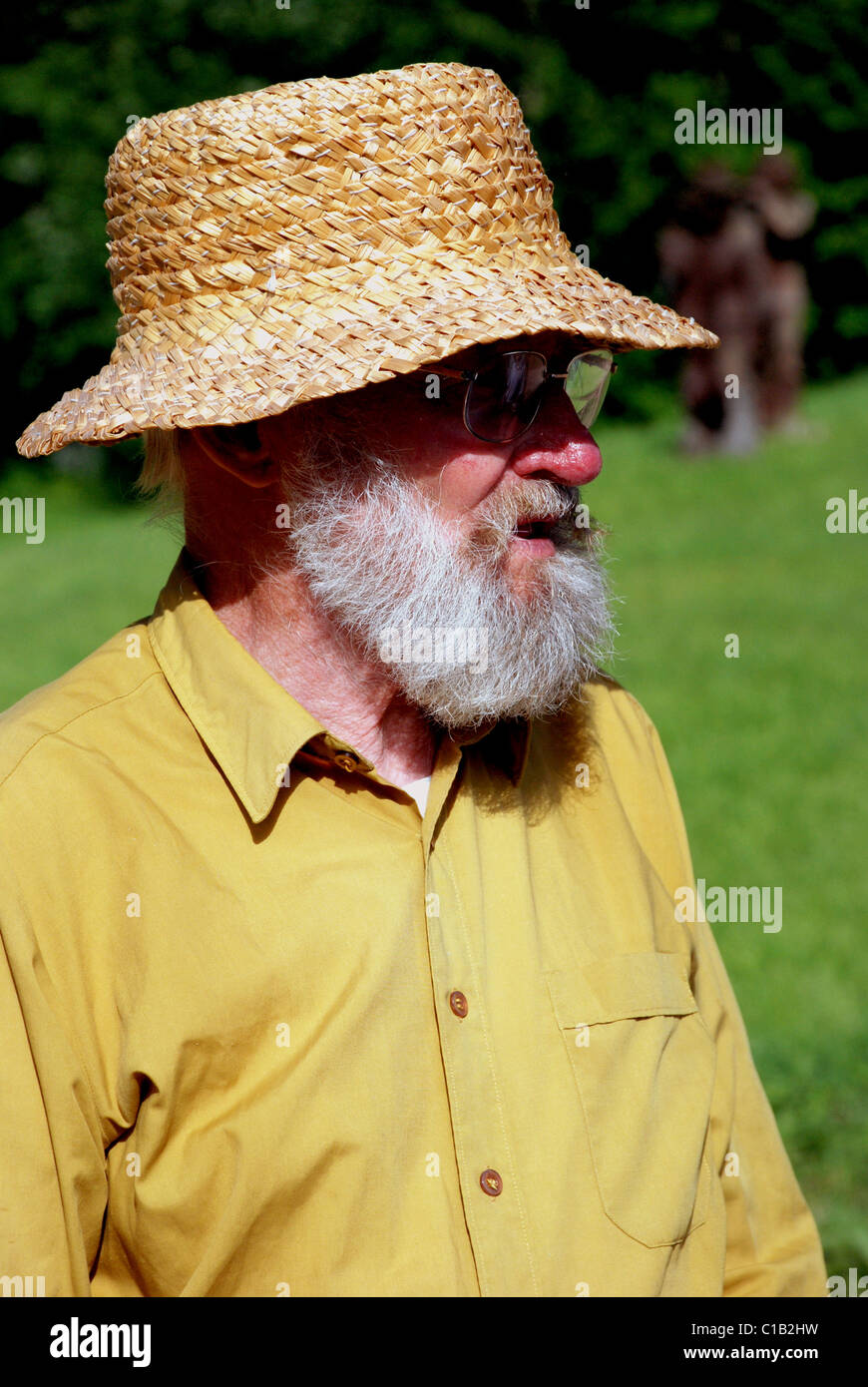 old man with grey beard and glasses wearing shirt in village Stock Photo