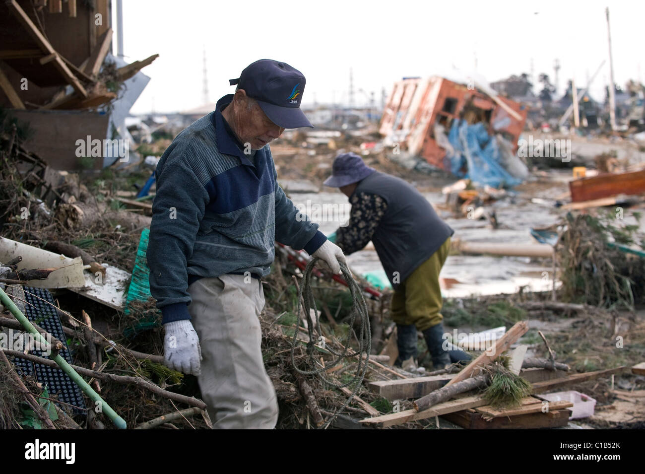 Isamu Higuchi and his wife Rie clear out debris that flattened their home by the mega-tsunami that followed the M9 quake, Japan Stock Photo