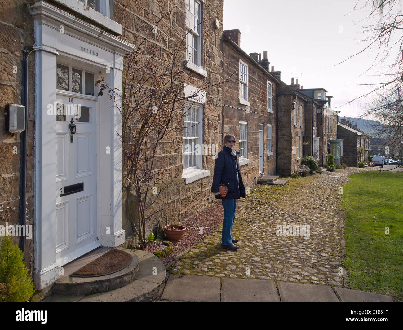 A woman tourist by traditional stone built cottages in North End Osmotherley North Yorkshire Stock Photo