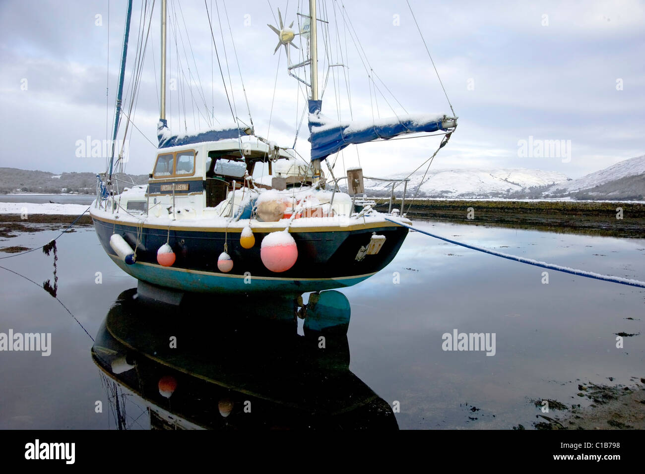 Moored ketch at low tide with covering of snow, Loch Etive, Argyll Stock Photo