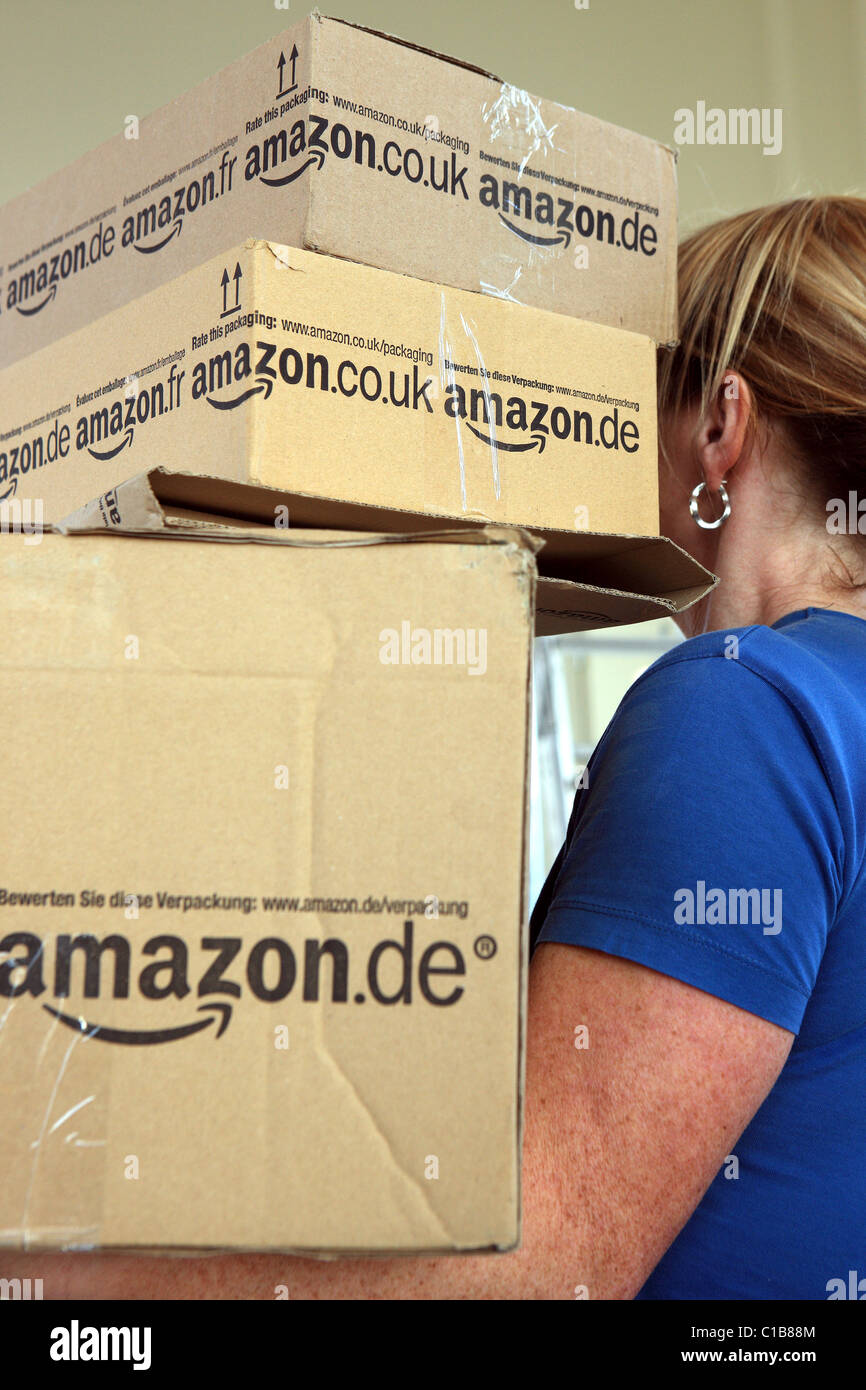 Woman carrying a stack of Amazon boxes Stock Photo