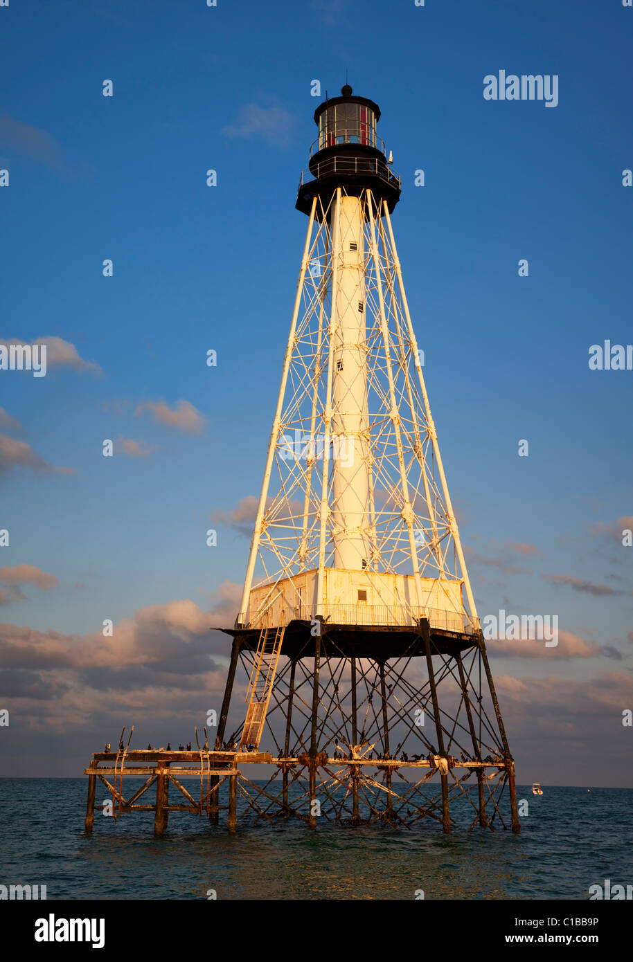 Glowing sunset background at open ocean Sombrero Reef Lighthouse protecting shallow reefs offshore Florida Keys USA beautiful blue sky background Stock Photo