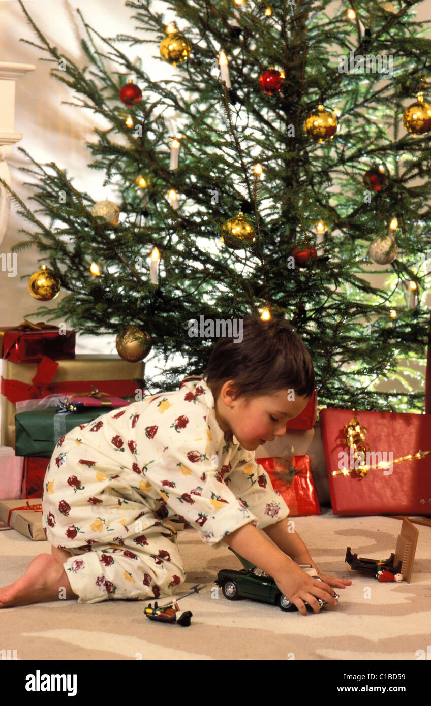 Christmas, little girl with her teddy bear in front of th chrismas tree ...