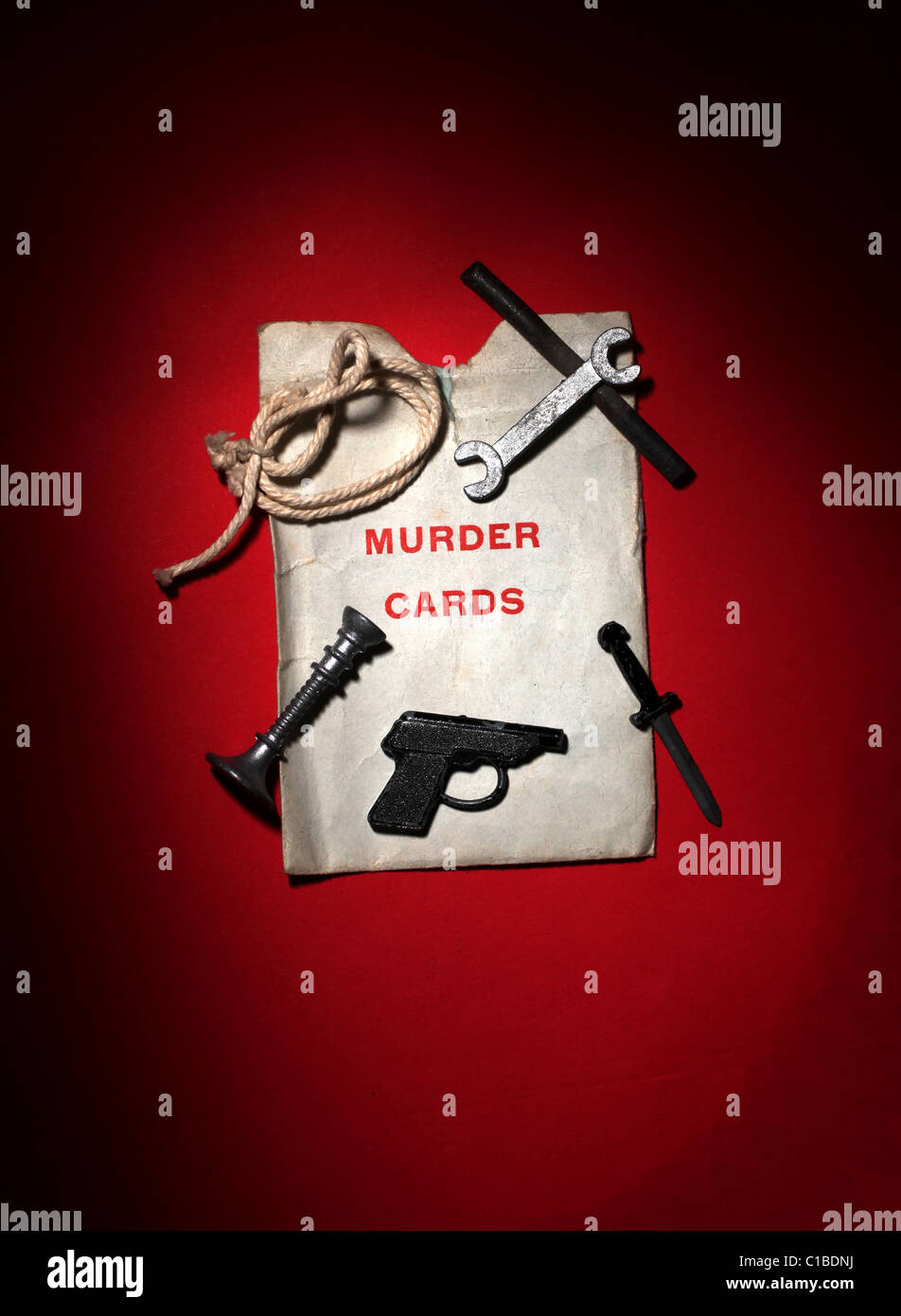 Details from the game Cluedo. The gun, lead pipe, rope, wrench and dagger and murder cards. Stock Photo